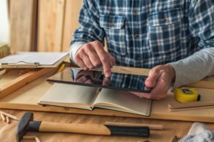 Carpenter using digital tablet to complete project to do list